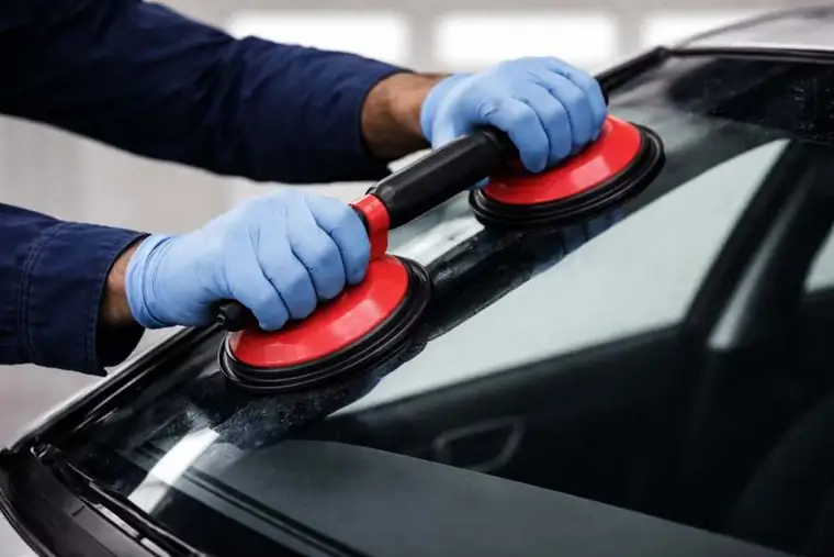 Auto glass replacement Houston technician using glass suction tools on windshield